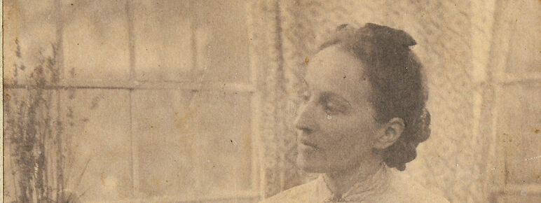 Mary Watts sitting down and tending to a plant on a window sill