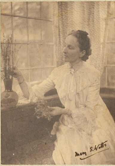 Mary Watts sitting down and tending to a plant on a window sill