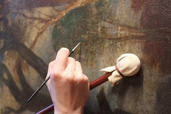 Close up of conserver's hand painting