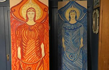 Two of the Compton angels, one painted red, the other blue, resting against a wall