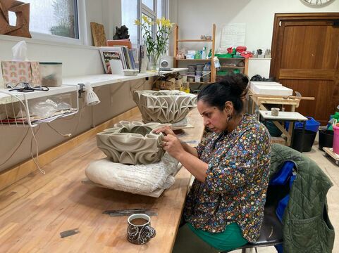 Halima sat at her workbench concentrating on carving a vessel placed on a pillow