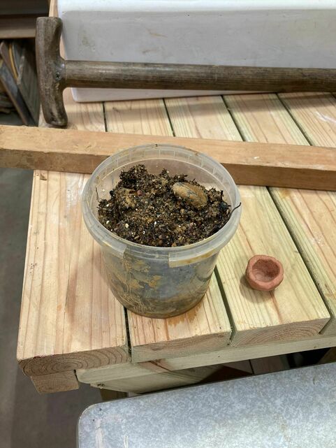 A tub of freshly dug Compton clay next to a small pot made out of the same clay after refined and fired