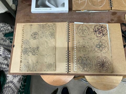 A closeup of one of Halima's sketchbooks, the brown paper filled with geometric design done in pen and ordered in neat rows