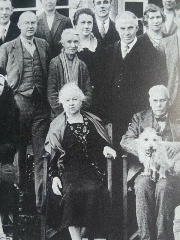 a black and white photograph of a group of people standing and sitting next to each other