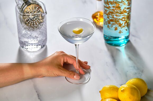 A woman holds a gin cocktail