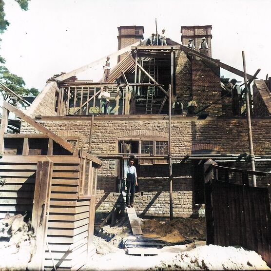 A colour photograph of Limnerslease being constructed by men working hard on the roof