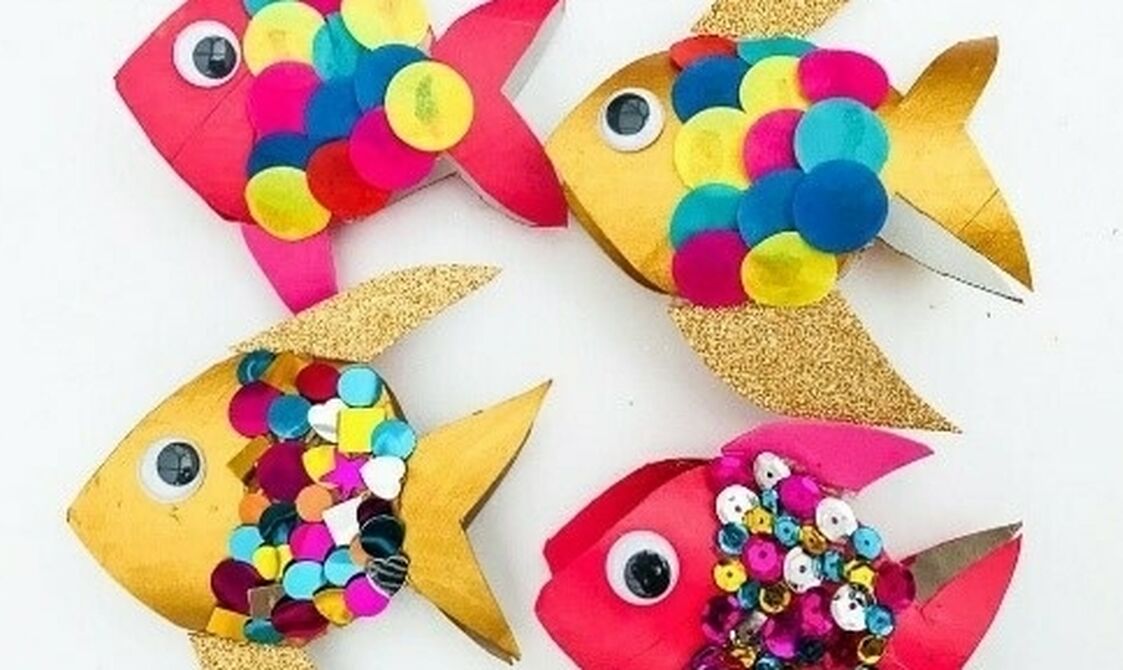 Four colorful paper fish crafts decorated with sequins, googly eyes, and multicolored paper circles on a white background.