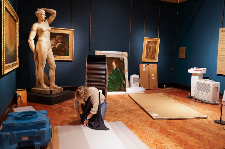 Photo inside Watts Gallery of conservator Sally Marriott preparing a painting for couriering