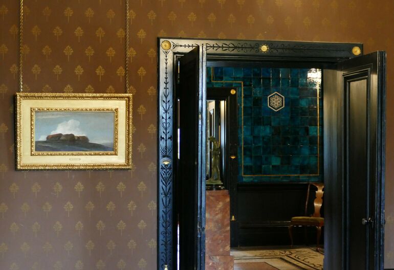 Photo of a painting hung inside the drawing room at Leighton House. It features a group of haystacks placed in a field