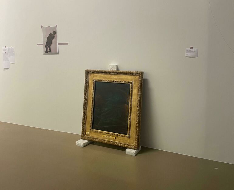 An oil painting in a gold frame sits on foam blocks in a white museum gallery