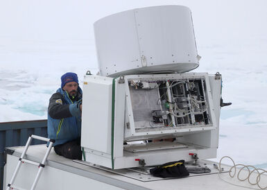 Photo of a man in the North Pole investigating a large white radar machine