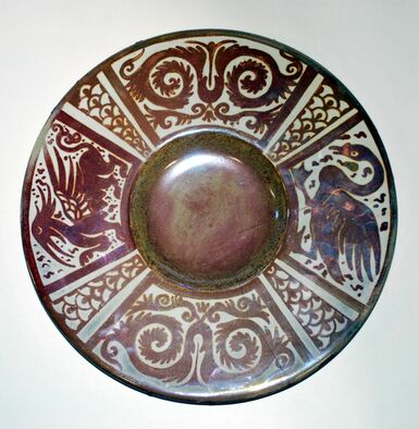 Decorative lustreware dish featuring a maroon and cream coloured geometric design as well as a dragon and a swan