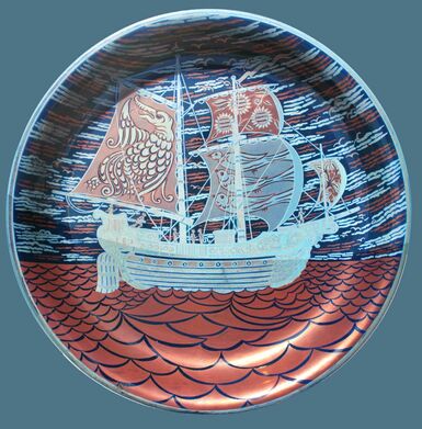 Lustreware dish of a blue ship on a red coloured sea, with red sails that have designs on them. The sky is a mixture of light blue, dark blue with bits of red throughout