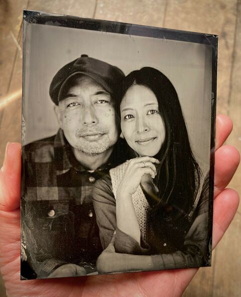 Tintype of a man and a woman posing together and looking at the camera. The man is wearing a flat cap and the woman has long dark hair that's straight.
