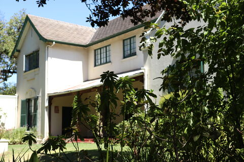 Photo of the Irma Stern Museum. The building is white and resembles a house with shrubs in the foreground