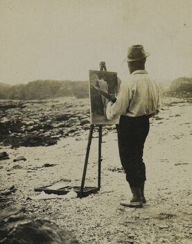 Sepia photo of a man painting at an easel on the beach