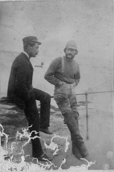 Black and white photo of two men talking on a beach