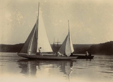 Monochrome photo of two figures in a small sailing boat on the water