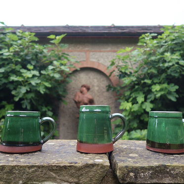 Three mugs with a green glaze lined up on the wall