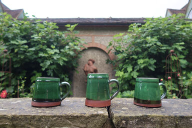 Three mugs with a green glaze lined up on the wall