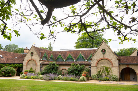 The exterior of Watts Gallery features triangular roofs, beige exterior and plants