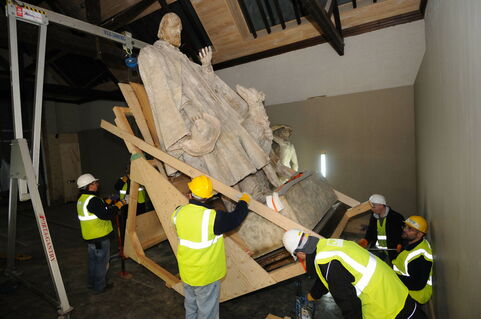 A group of high-vis workers move the large, plaster model of Tennyson