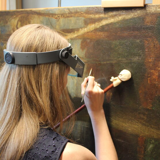 Conservator uses brush to restore painting