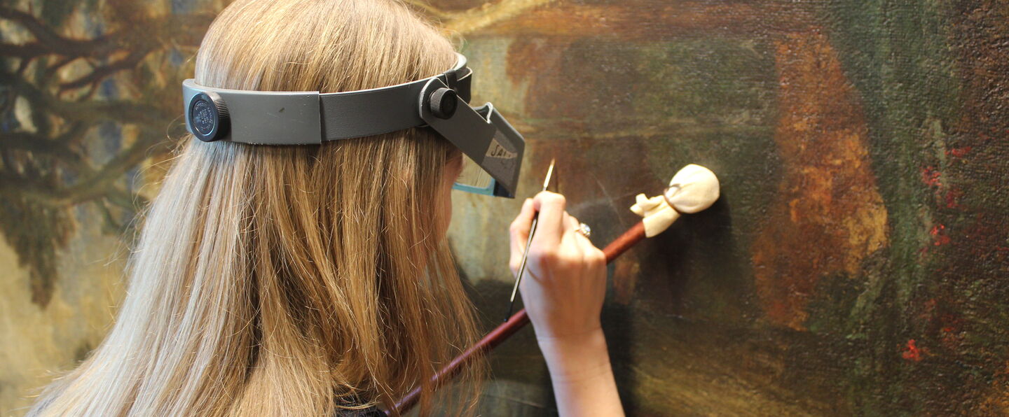 Conservator uses brush to restore painting