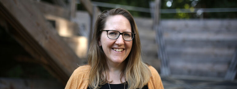 Claire stands in front of our wooden auditorium, she smiles to the camera