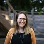 Claire stands in front of our wooden auditorium, she smiles to the camera