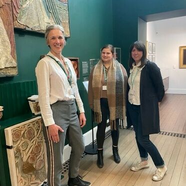 A photo of three women stood in the Mary Watts Gallery together smiling