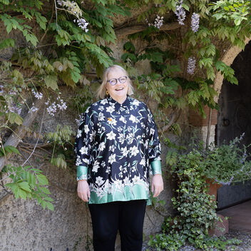 A photo of Sarah King, a lady with short blonde hair wearing glasses and a patterned shirt