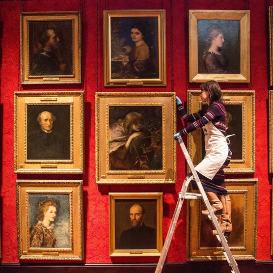 Woman on ladder looking at paintings