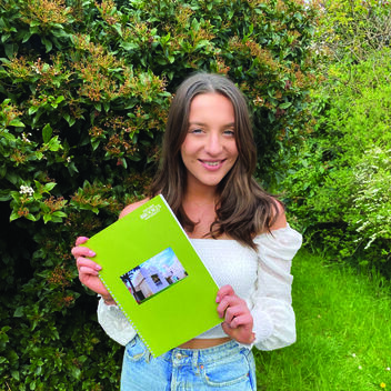Bryony holds her dissertation and smiles to the camera