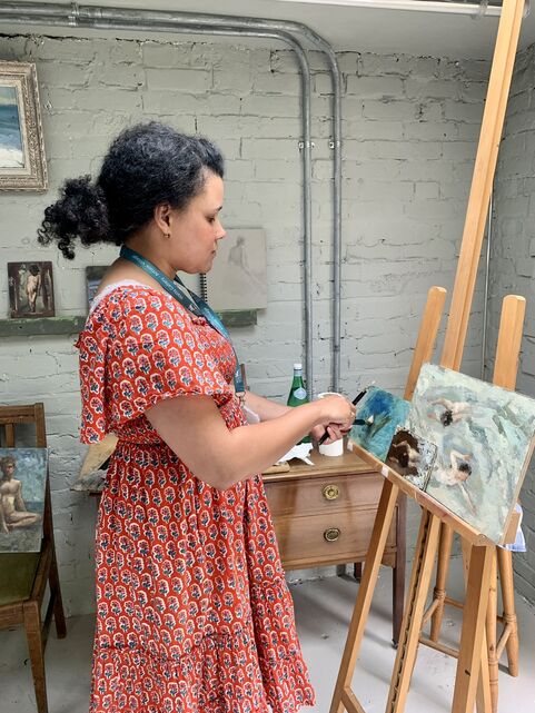 Nneka painting on an easel