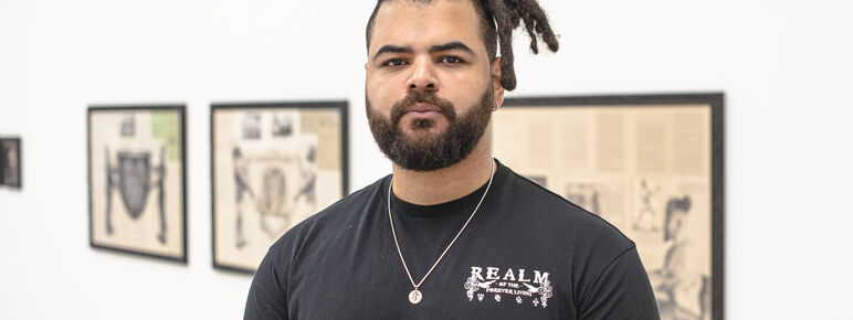 Artist Habib Hajallie in a black shirt wearing a gold necklace. He looks straight into the camera