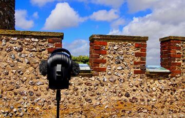 Photo of a microphone on a tripod in front of a stone wall