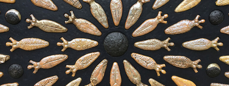 A bronze and black artwork featuring women shapes in a circular pattern