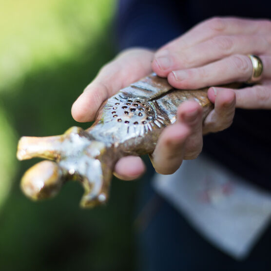 A hand holding a bronze women-figure