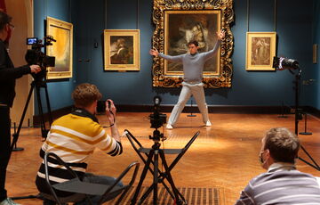 A dancer for Chris Pavia's Beyond the Waves dances in front of Francesca and Paolo. A crew photograph and film him in the foreground