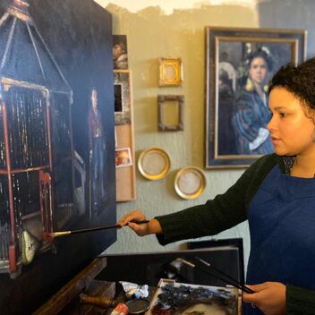 Artist Nneka Uzoigwe paints at an easel in her studio
