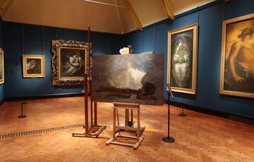 A collection of paintings on easels placed in the centre of the Watts Historic Gallery as part of an intervention
