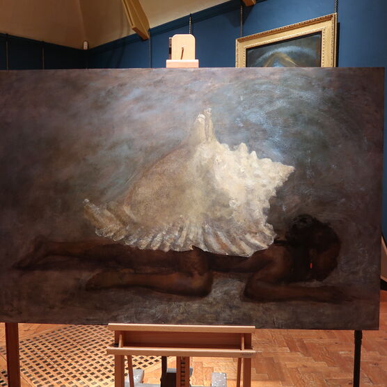 An oil painting on an easel of a large sea shell on the back of a sprawled, dark figure.