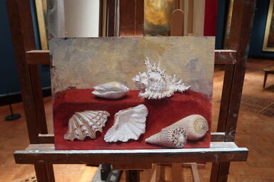 An oil painting on an easel of a collection of large sea shells on a red cloth