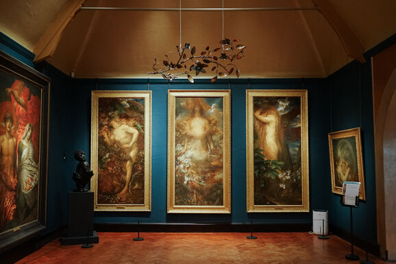 Photo of the inside of Watts Gallery. Suspended from the ceiling is a copper sculpture of flowers and vines
