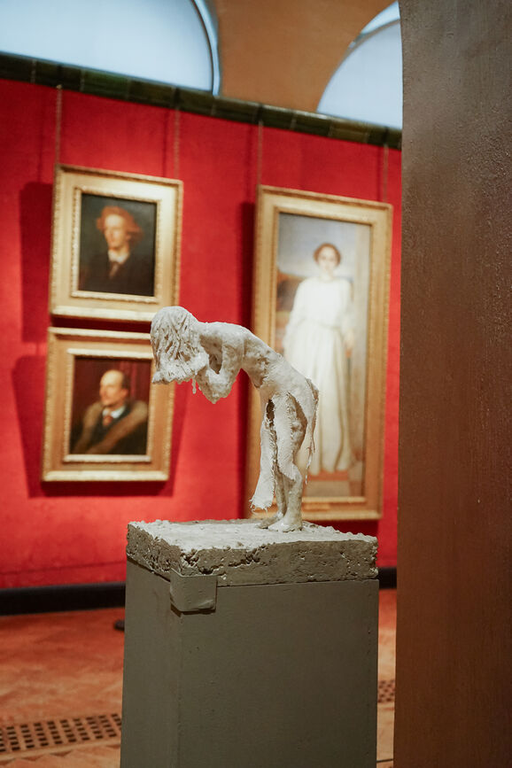 Small sculpture of the female form bent over with her head in her hands. It looks like she's crying