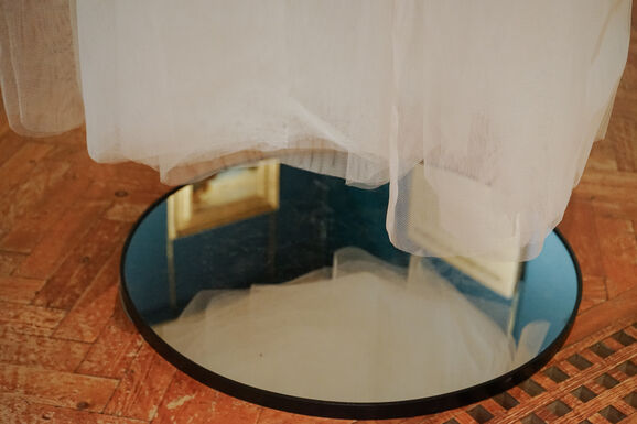 Photo inside the Historic Galleries at Watts Gallery. This is a close up image of the bottom of an installation hanging from the ceiling made from tulle with a mirror underneath