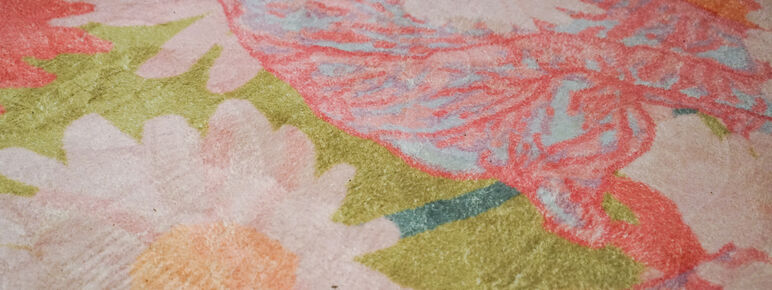 Close up photo of a pink and green rug. The rug is decorated with a floral pattern