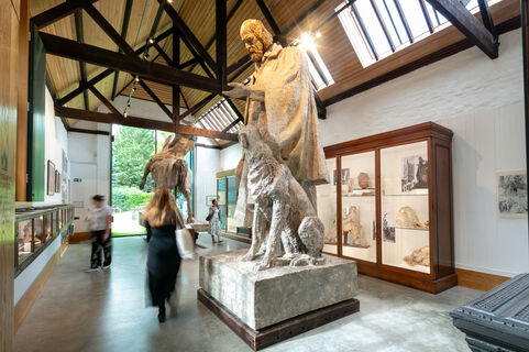 Visitors walk through tall ceiling gallery full of large sculptures