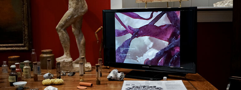 Photo of a monitor screen playing a moving image video with other small objects placed beside it.